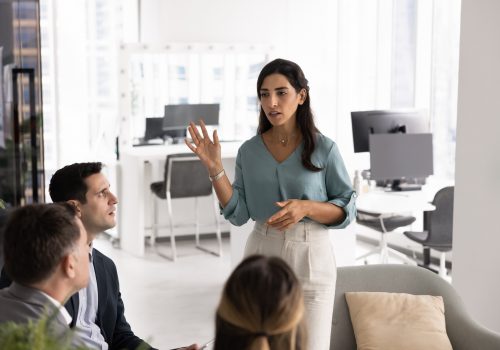 Serious Latina businesswoman speaks, stands confidently in front of small group of colleagues, lead presentation or discussion, engaged in briefing event, team meeting, collaborative strategy session SSUCv3H4sIAAAAAAAACmxSS27UQBC9Sugd0jTqn+3uWbPlBHEUVf9mmnjske0JRNFI7OEAEUKRQBwgAiEhIe7QuRHVziA2LNyuqn6vPq/6lliYkiPrW5K67jDNI8xp6MmarcgYeh/GxbweZc0WC9LyCz7Nw5igWzwLs9v2sAtk3R+67rgi0wzzYQoTJkbPwRw2CF/8vxXPb0ucrAlB+MEW47j6T+wCi25C724K148BdtOcSqnzguJC4NkYUmAd7G5O8doKU0nfUKG1oIpVhlomDfWiMV5LzqX15OKIzY2hC7C0ek6ANx4gSqqZBaqiBGqY1DSwymsrAgQhMTnjDWeN4LR2MVAllaFGgKWxUuCiq2MdLMI0CGa15tRGb6hSxlPg1lMTYsWYcJaHCmECQhO5jtRjh1Q5VVOjraHBS2MaI5ngTRnv6s0cxt1JUjj4NBRFrgcHHQZlCaY9jPAXsh+TS/3myRnmbdkl6jsc+nlEmYpK3TDswXYoZsQkYUW2ME0I8KdA2R0+imH3lKQf5qJTYXpcKVpcSiObWnFW1Q0KIXnZ3LL8bUJiKVSYaLqr5E+dJcxPKsdkVKyhVipPVc0CNV4GqpXWzoBxPJRkh303gJ/LrMiMw7hbHsgIE6qxjIDz72HeYvDlum2fneXP+Uu+zx/zXdvm+8d3+Wf+jt/v/JB/Pb5vW8GEejovmbjMX/OP/A1R5fZD21bPz16ltxEf81n+lB8WOlIx1d0/2/AXr/cbcvwDAAD//wMAoTLnej8DAAA=