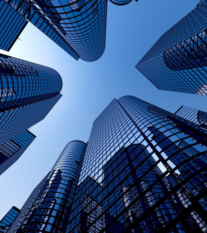 Low angle shot of modern glass city buildings with clear sky background.