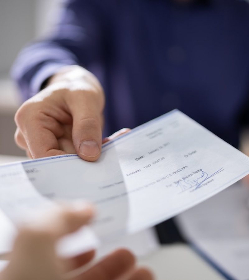 Businessperson Hands Giving Cheque To Other Person
